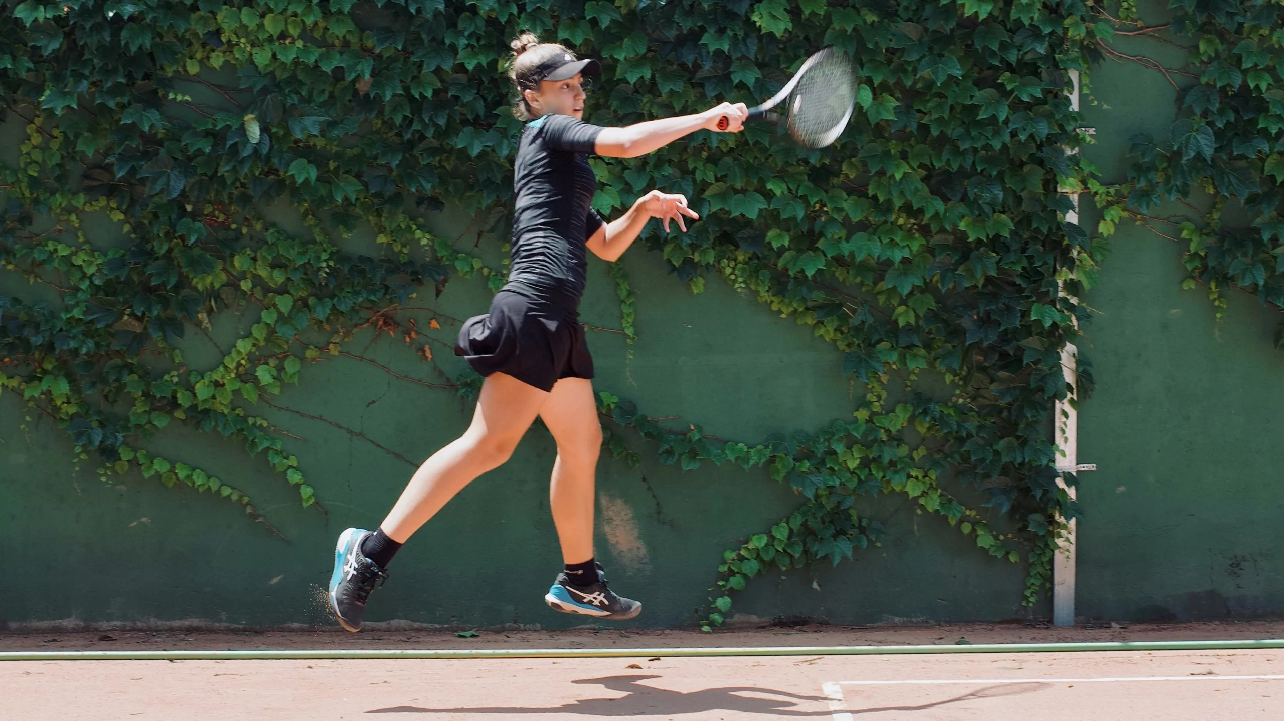 Female tennis player in extension after hitting the ball.